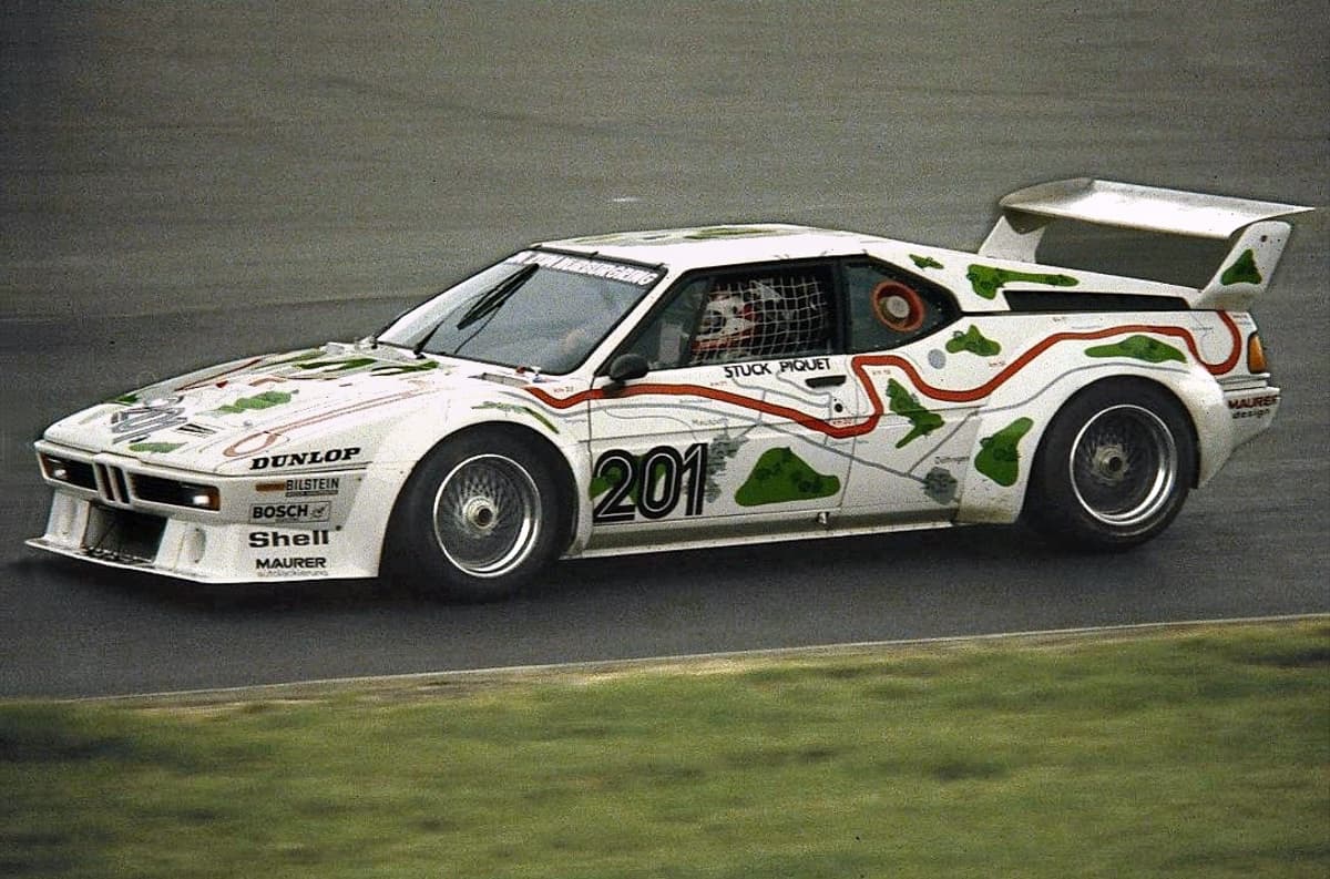 The white BMW M1 number 201 with green map shapes, seen from the front three-quarter from the left, in practice at the Nürburgring.