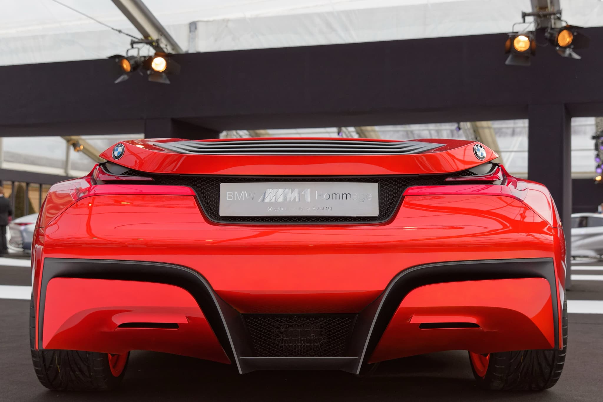 The BMW M1 Hommage from directly behind, with a roundel at each tail corner, the louvred rear window and a name plate. Opens a larger view