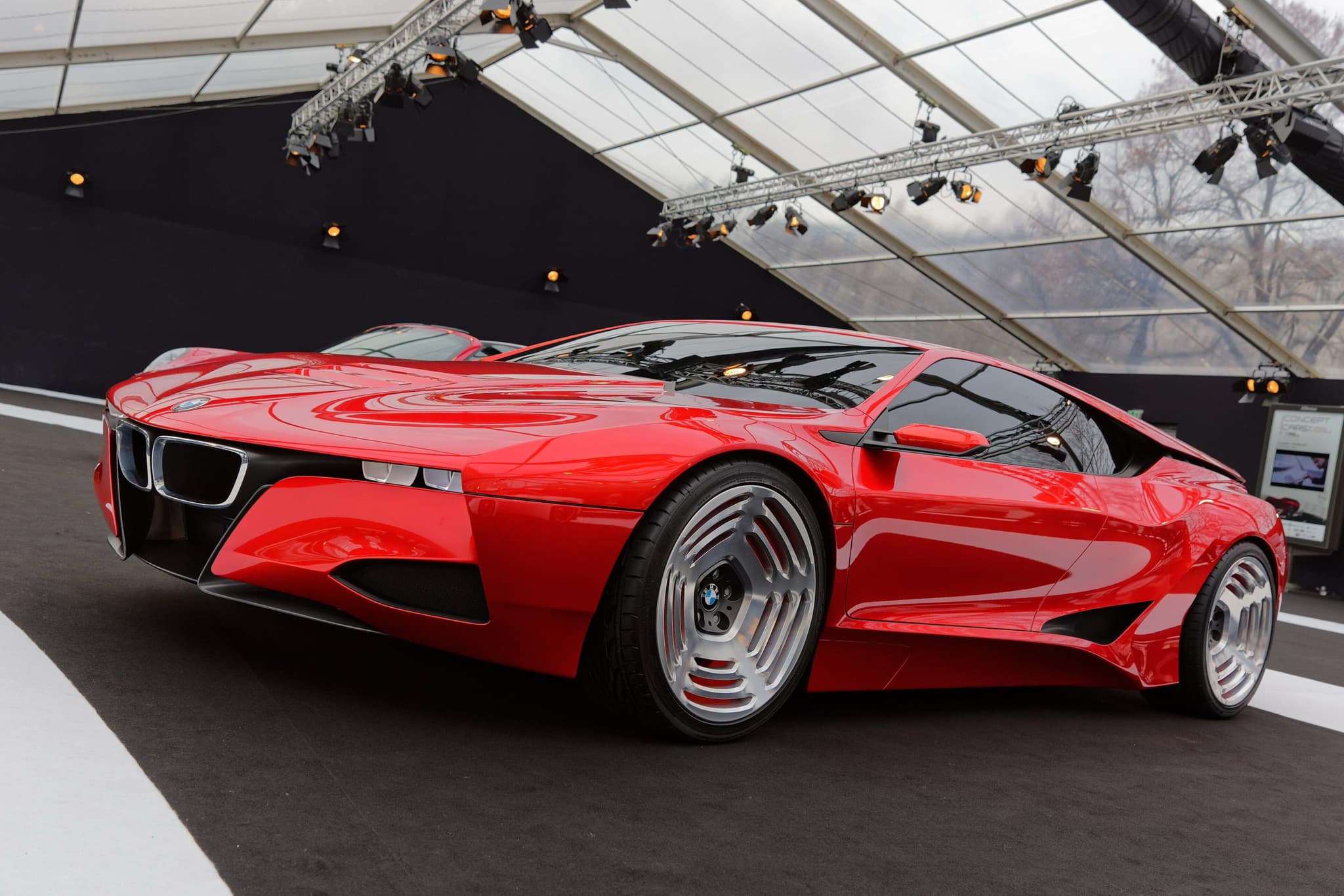 The red BMW M1 Hommage concept under a show tent, front three-quarter from the left.